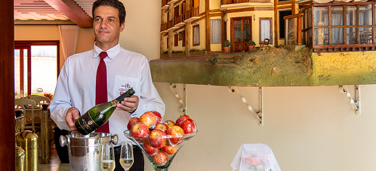 Colaborador da Pousada D'Biagy Raízes servindo welcome drink com espumante e frutas frescas na recepção