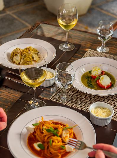 Pratos gourmet e taças de vinho branco servidos com elegância na Pousada Família D'Biagy.
