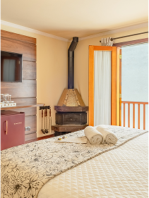 Quarto de pousada com lareira acesa e cama confortável na Pousada D'Biagy Raízes