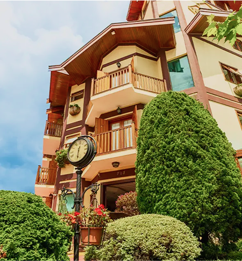 Fachada da Pousada D'Biagy Raízes em Campos do Jordão, com arquitetura charmosa em estilo serrano e exuberantes jardins.