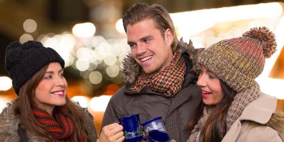 Grupo de amigos agasalhados, sorrindo e tomando algo quente, aproveitando o Feriado de Corpus Christi em Campos do Jordão, marcando a abertura da temporada de inverno.