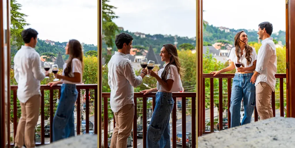 Casal brindando com taças de vinho em uma varanda com vista panorâmica da cidade, celebrando o Dia dos Namorados na Pousada Família D'Biagy.