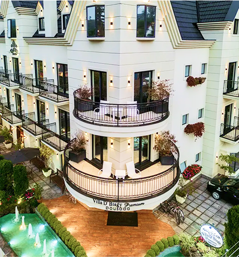 Fachada luxuosa da Pousada D'Biagy Premium em Campos do Jordão, com arquitetura europeia e espelho d'água na entrada.