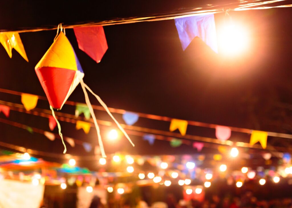 Decoração de festa junina com bandeirinhas coloridas e luzes, representando o pacote especial de Feriado de São João na Pousada Família D'Biagy em Campos do Jordão.
